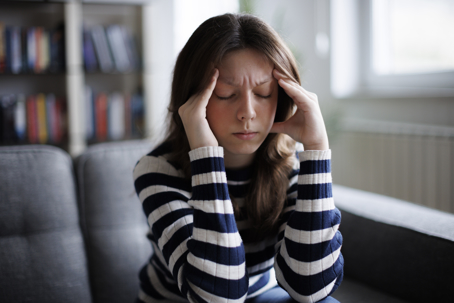 Woman sitting on sofa feeling dizzy.